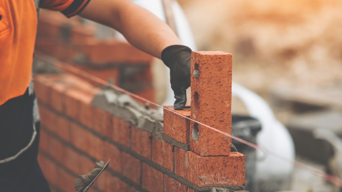 Construction Worker Placing Brick in Brick Wall During Daytime; Shutterstock ID 2482727779
