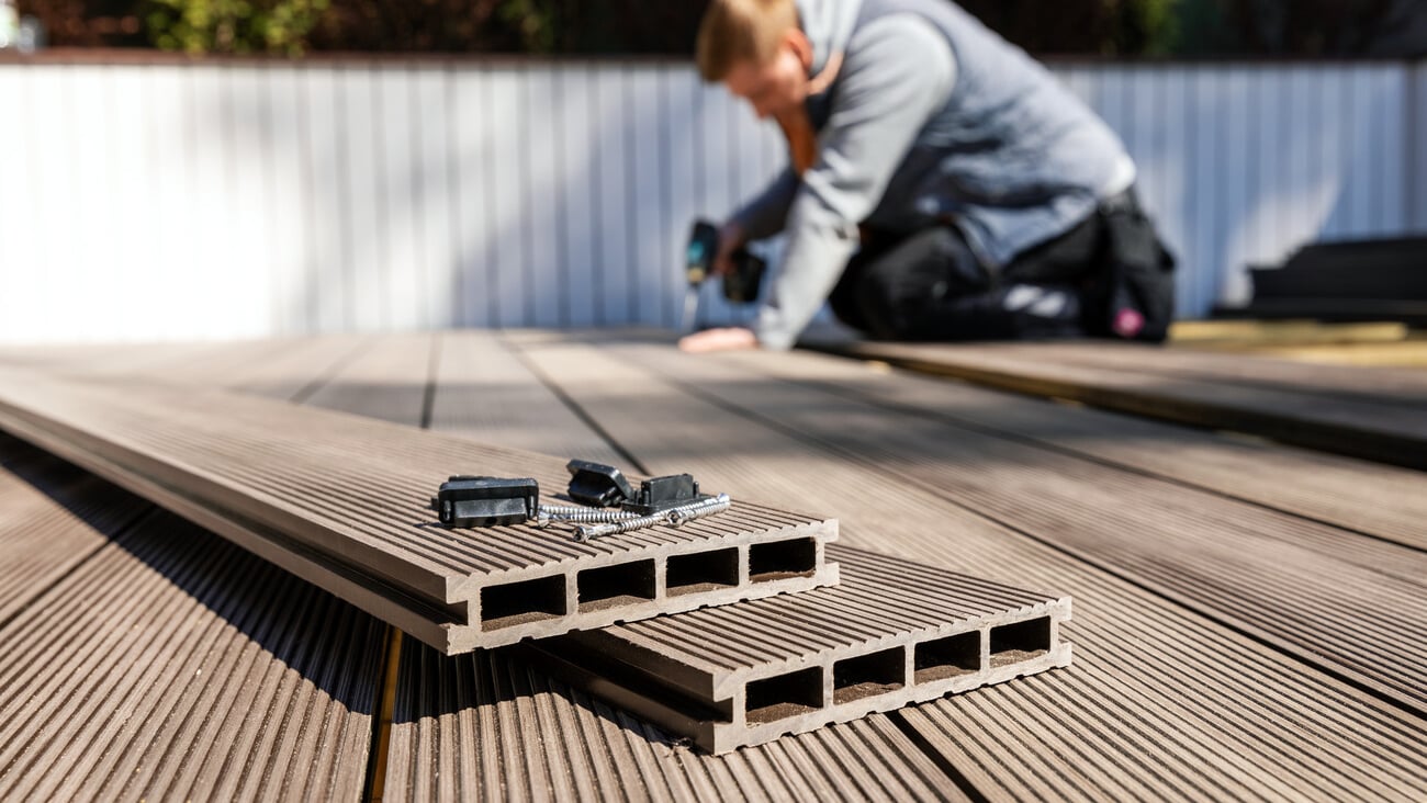 wpc terrace construction - worker installing wood plastic composite decking boards; Shutterstock ID 1717895287