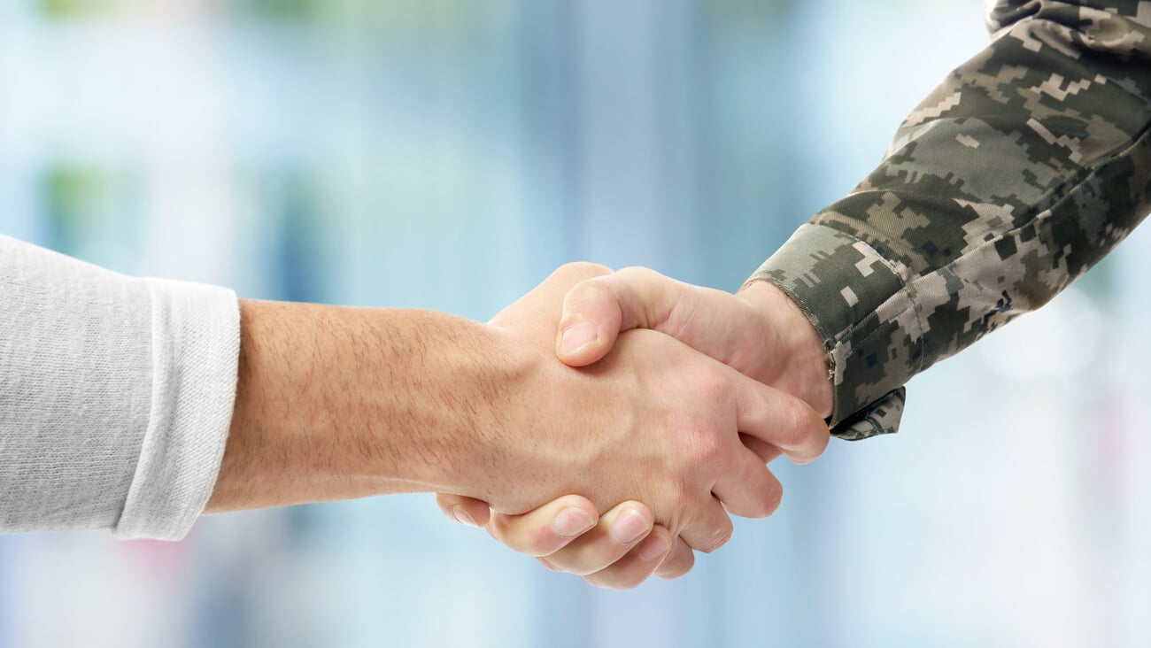 Soldier and civilian shaking hands on blurred background; Shutterstock ID 606183713