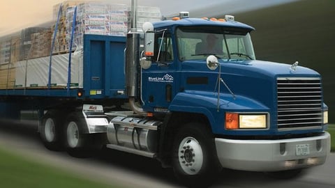 a large blue truck is driving down the road