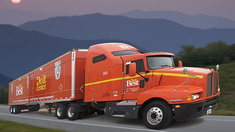 a large orange truck with a mountain in the background