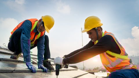 Construction worker wearing safety harness belt during working on roof structure of building on construction site,Roofer using air or pneumatic nail gun and installing concrete roof tile on top roof.; Shutterstock ID 1676783290