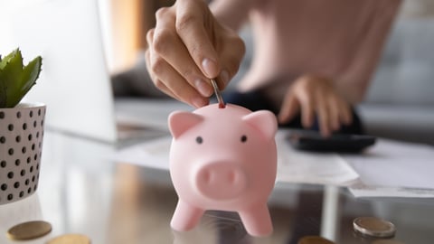 Close up young female putting coin in piggy bank. Woman saving money for household payments, utility bills, calculating monthly family budgets, making investments or strategy for personal savings.; Shutterstock ID 1714288111