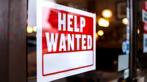 Sign text closeup for help wanted with red and white colors by entrance to store shop business building during corona virus covid 19 pandemic; Shutterstock ID 1840085851
