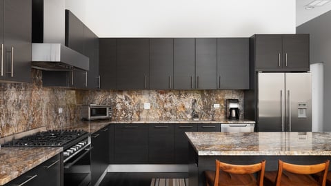 CHICAGO, IL, USA - JUNE 28, 2021: A modern kitchen with brown cabinets, granite countertops, bar stools sitting at the large island, and Fisher  Paykel stainless steel appliances.; Shutterstock ID 2172502733