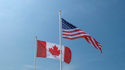 USA and Canadian flags waving left to right against blue sky. Economy, politics, partnership, external affairs concept.; Shutterstock ID 2395461801