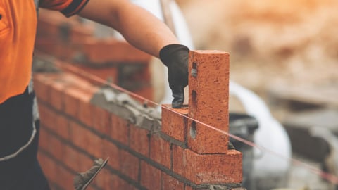 Construction Worker Placing Brick in Brick Wall During Daytime; Shutterstock ID 2482727779