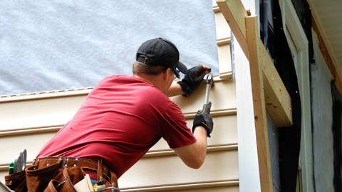 Young homeowner installs siding to his home.  He is holding a hammer and wearing a tool belt.; Shutterstock ID 137667209