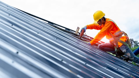 Roofer worker in protective uniform wear and gloves, using air or pneumatic nail gun and installing asphalt shingle on top of the new roof,Concept of residential building under construction.; Shutterstock ID 1517753627