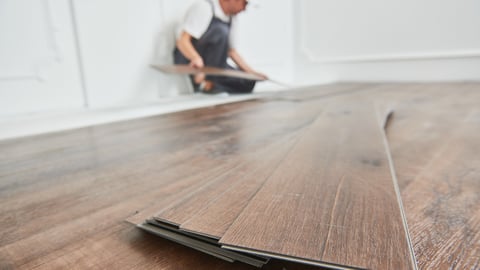 worker laying vinyl floor covering at home renovation; Shutterstock ID 1584436756