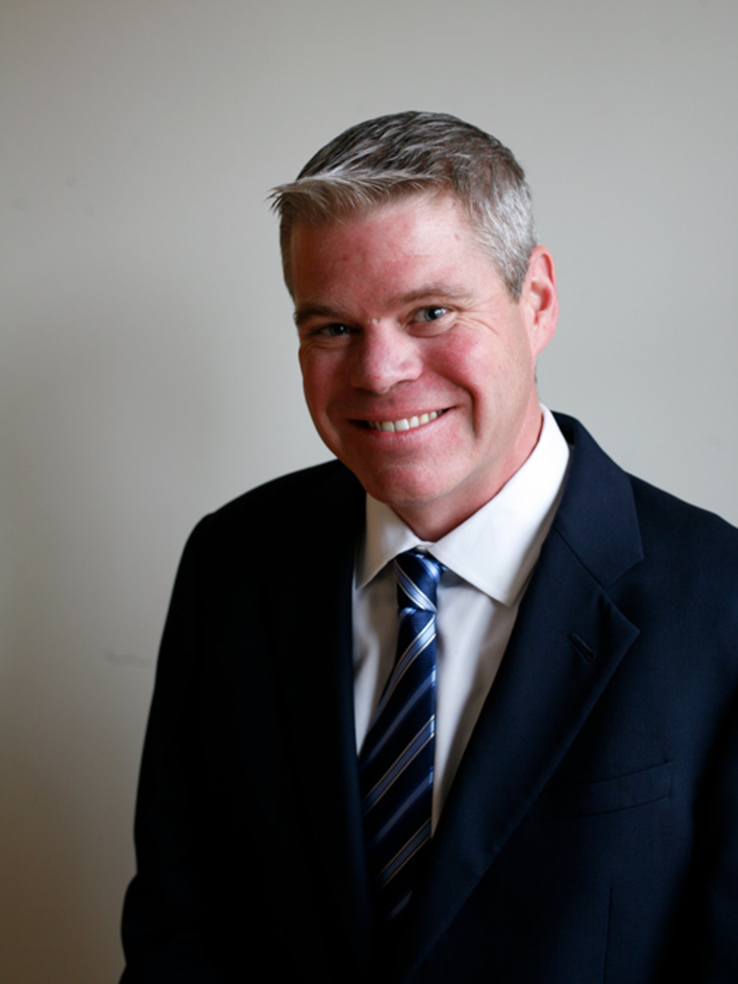 a man wearing a suit and tie smiling at the camera