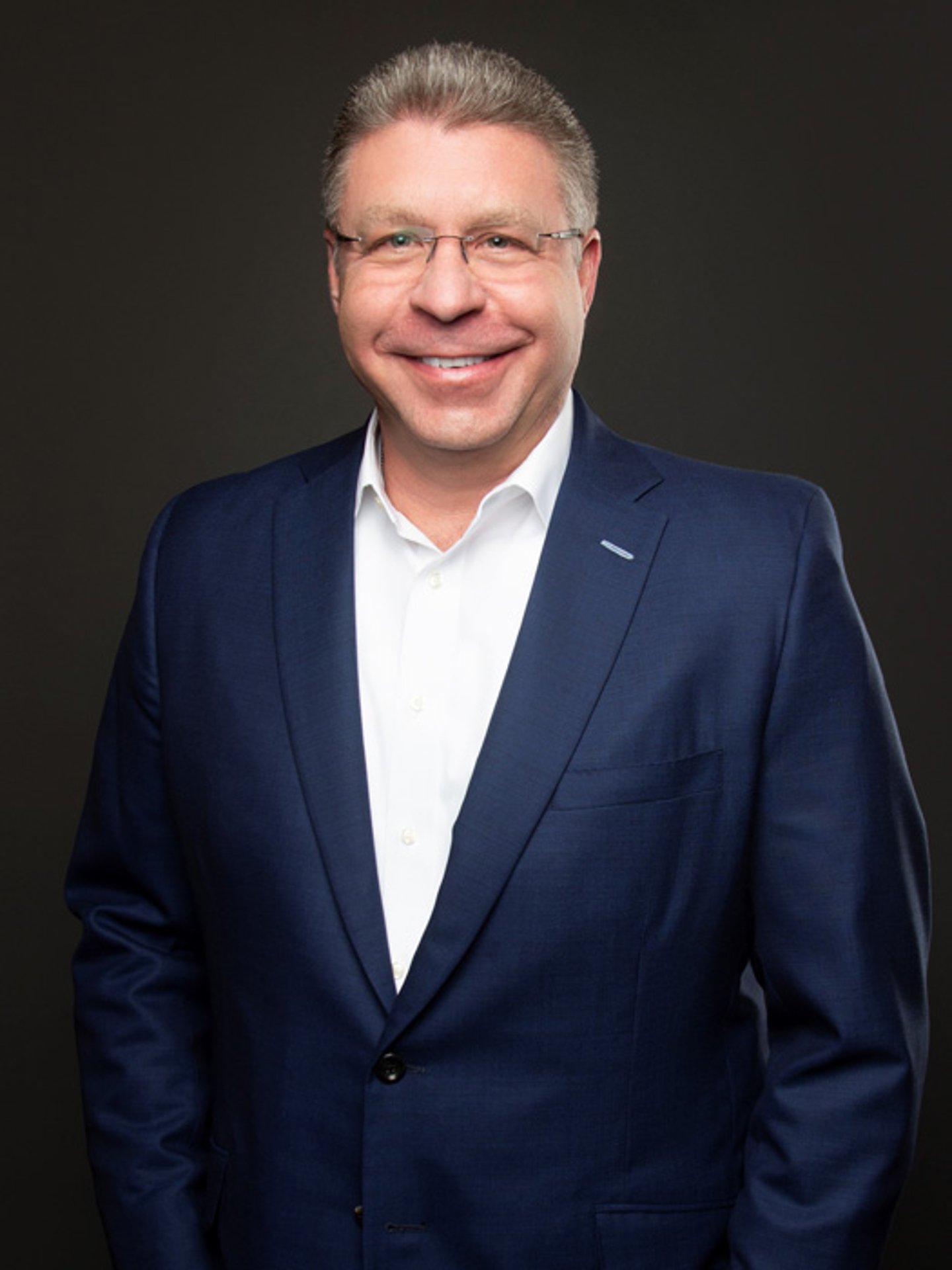 a man wearing a suit and tie smiling at the camera