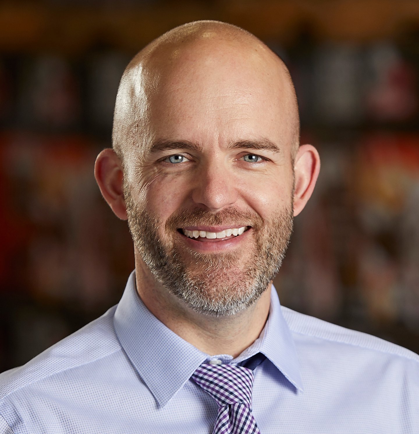 a man wearing a suit and tie smiling at the camera