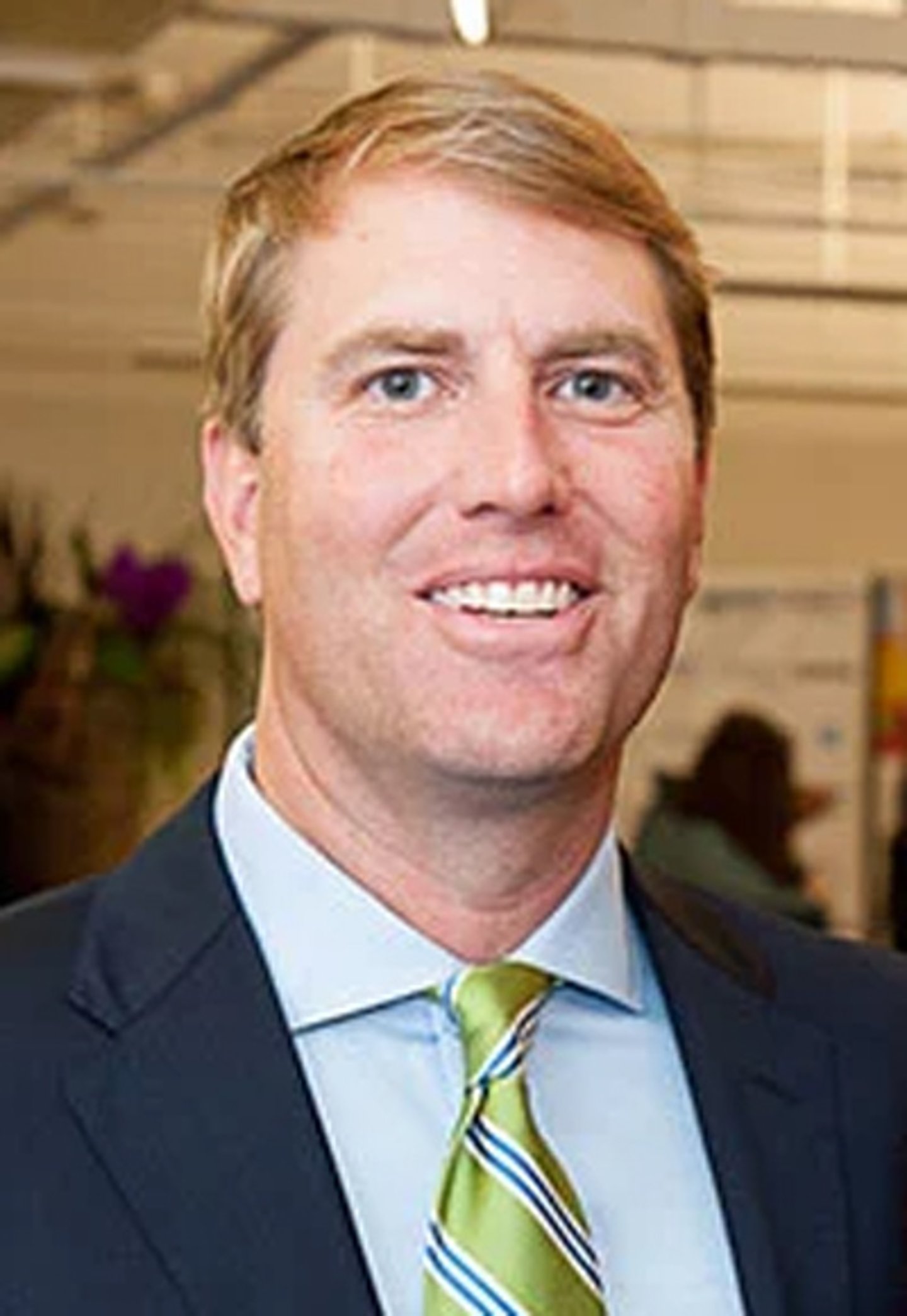 a man wearing a suit and tie smiling at the camera