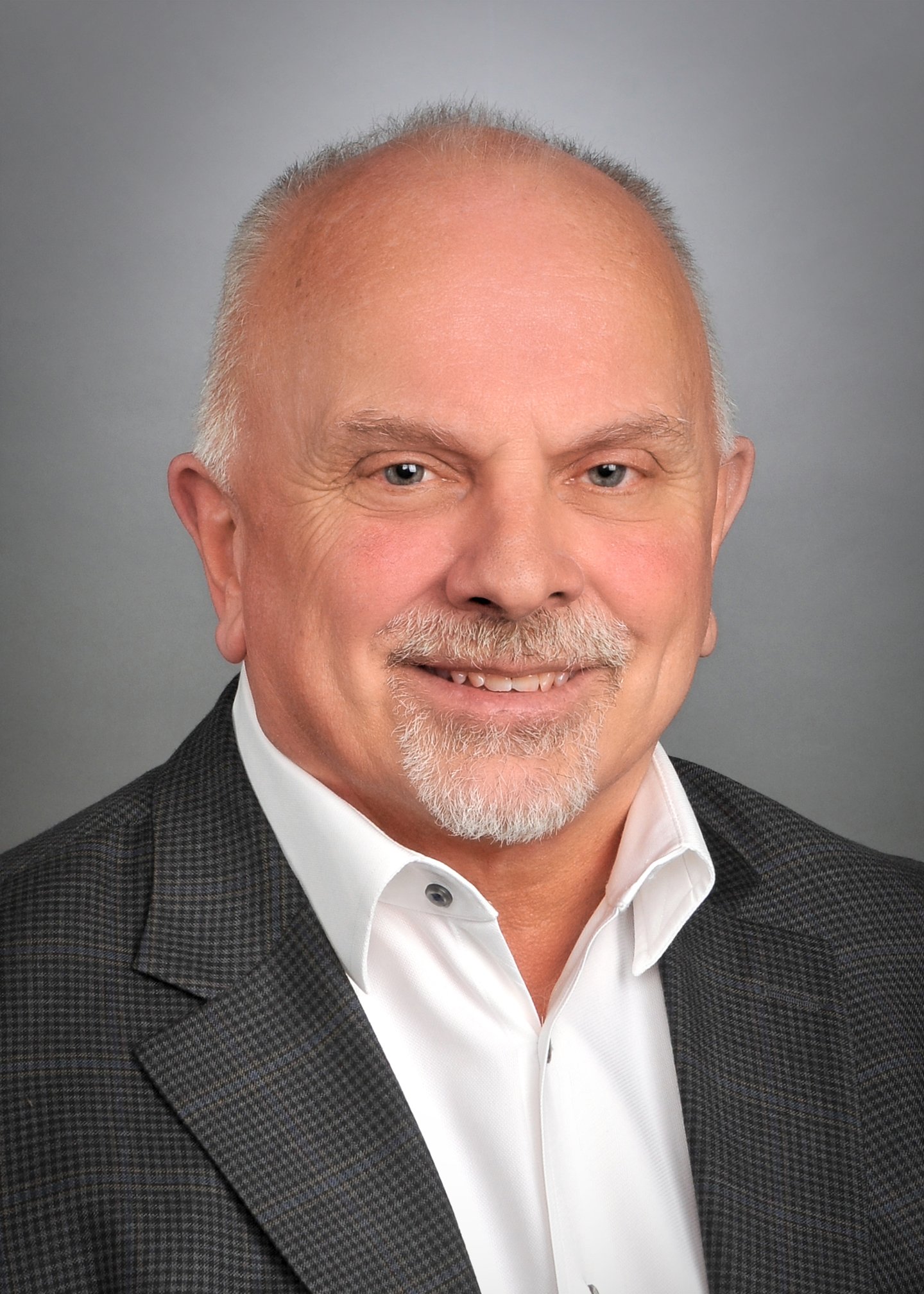 a man wearing a suit and tie smiling at the camera