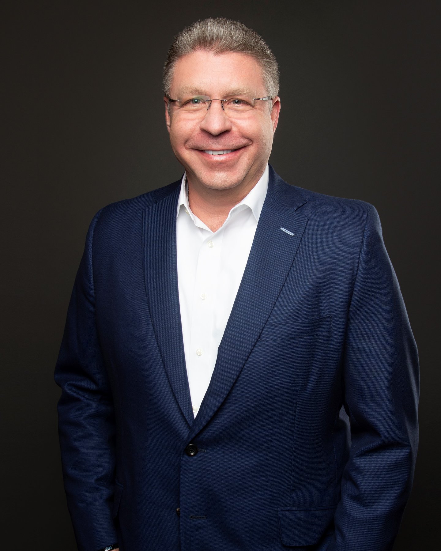 a man wearing a suit and tie smiling at the camera