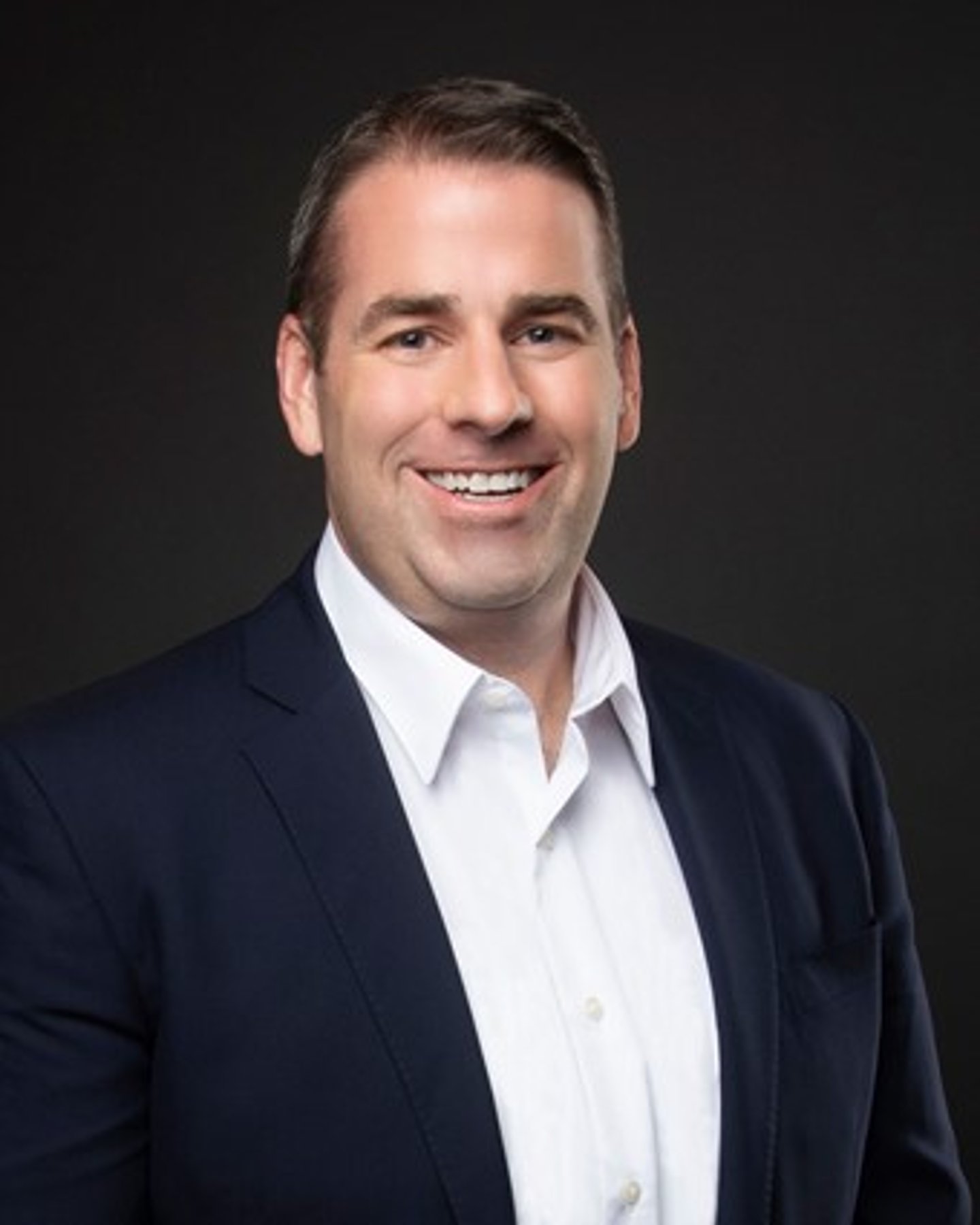 a man wearing a suit and tie smiling at the camera