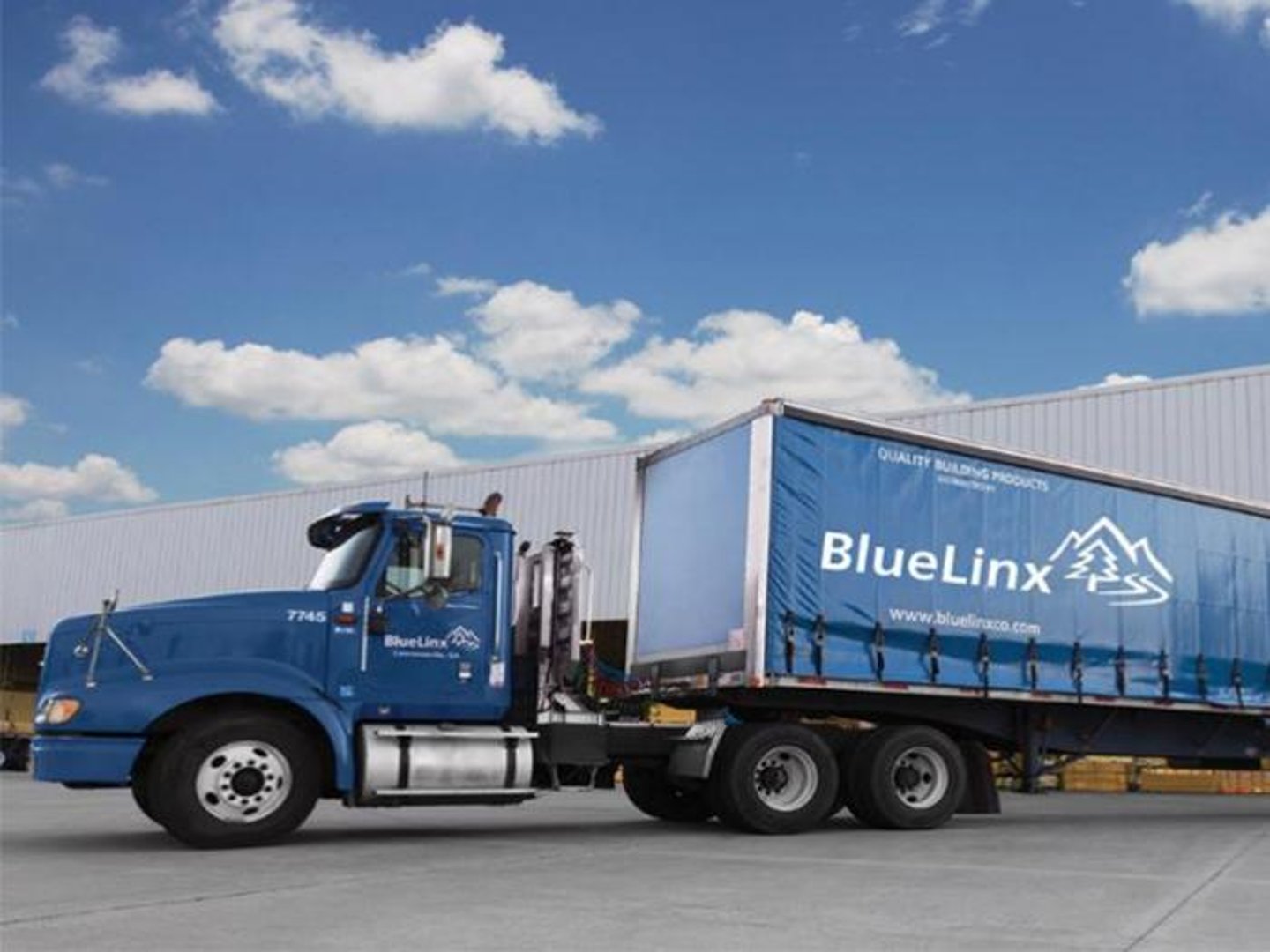 a large blue truck is parked on the side of a road