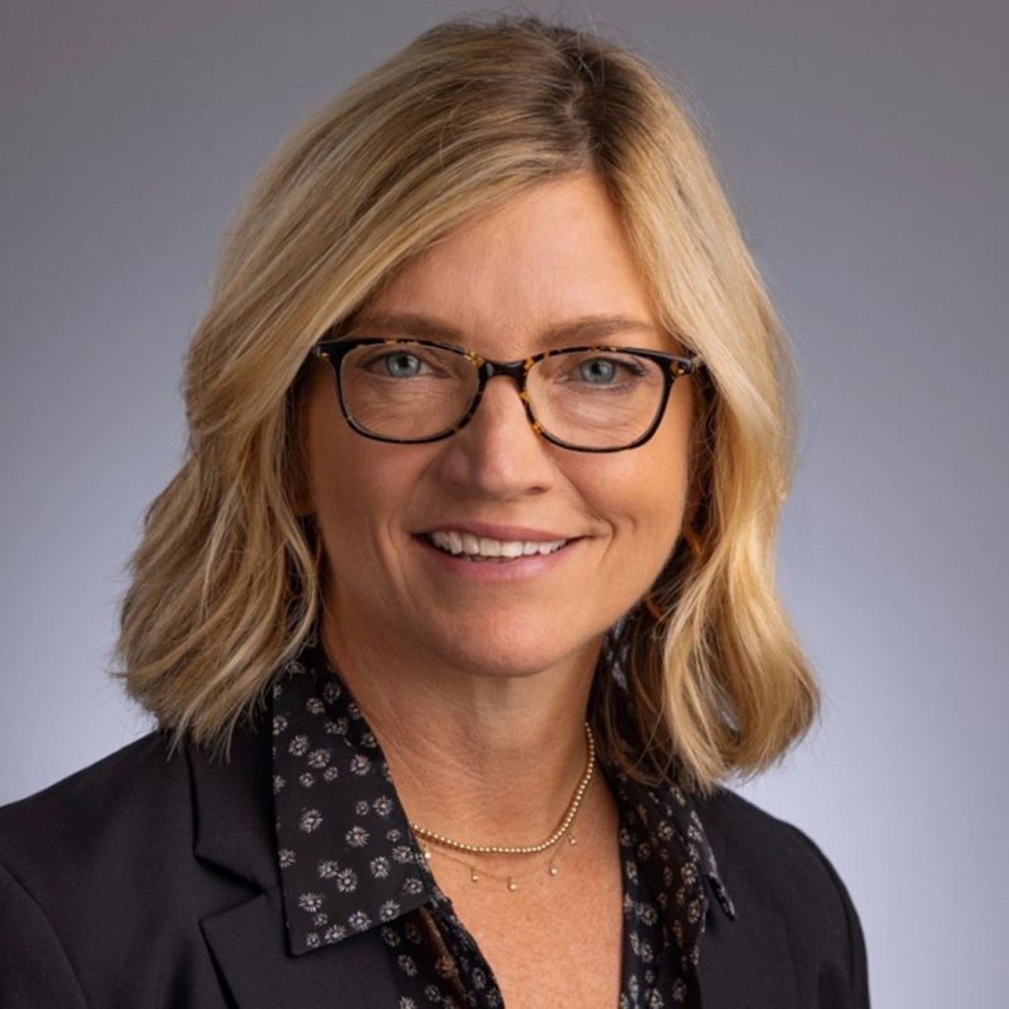 a woman wearing glasses and smiling at the camera