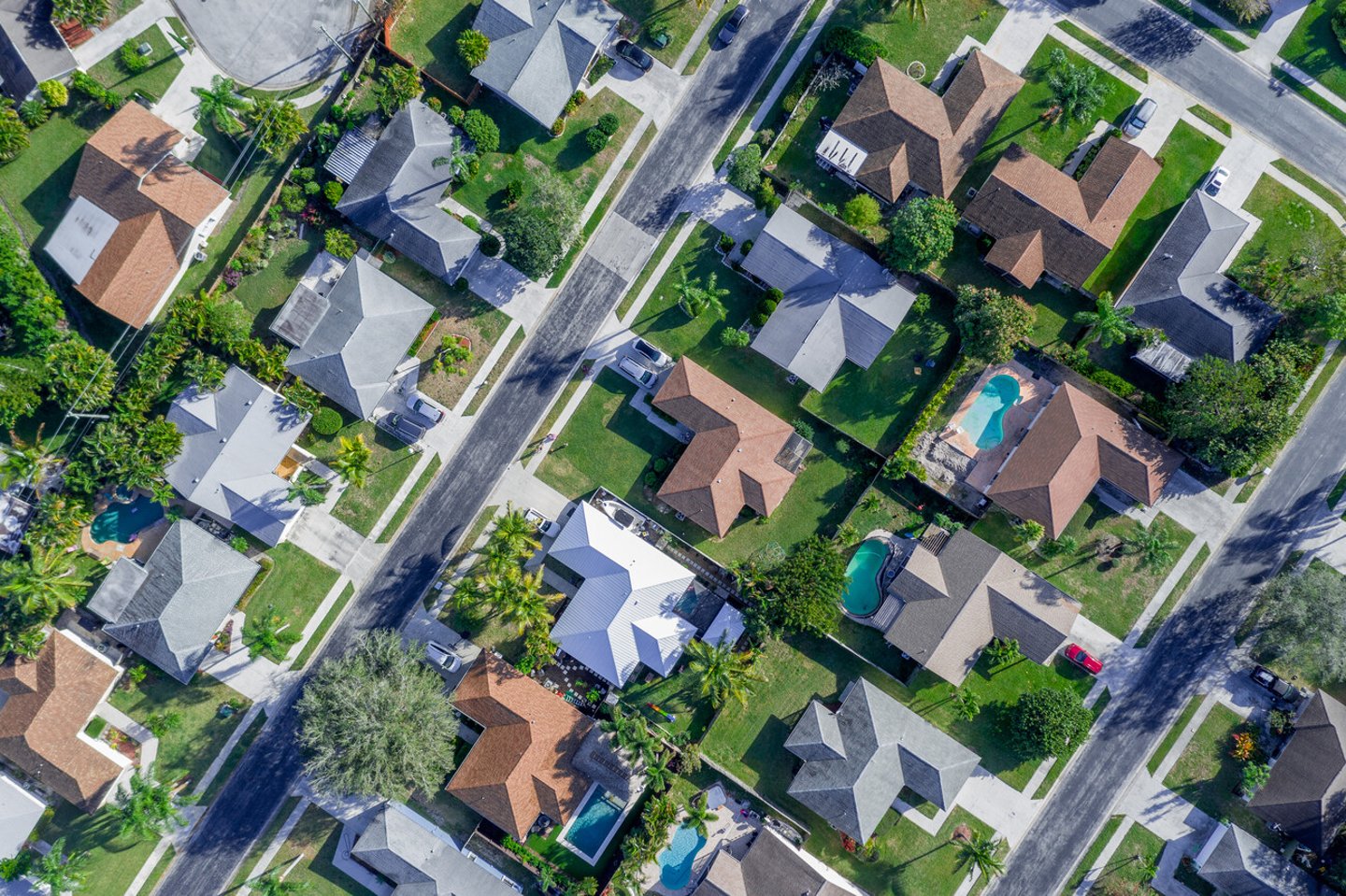 Aerial summer view of warm sunny neighborhood community roofs with diagonal streets and lots of houses with pools and palm trees. ; Shutterstock ID 1318716863