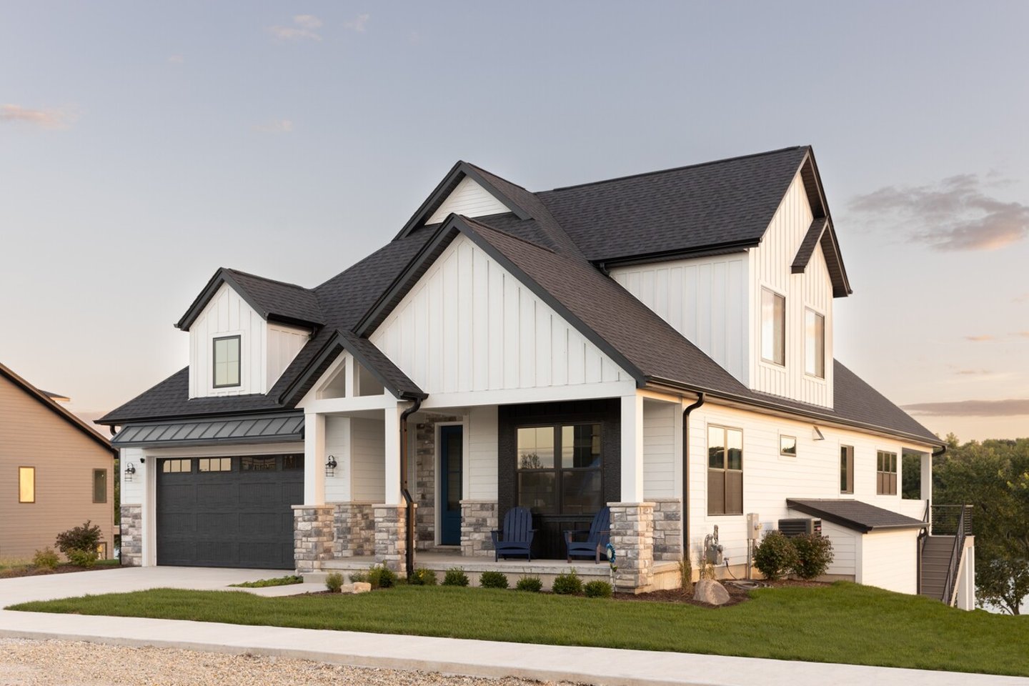 ELMHURST, IL, USA - SEPTEMBER 25, 2022: A black and white luxury home with a two car garage and black door, professional landscaping, and a lake in the background at sunset.; Shutterstock ID 2245365837