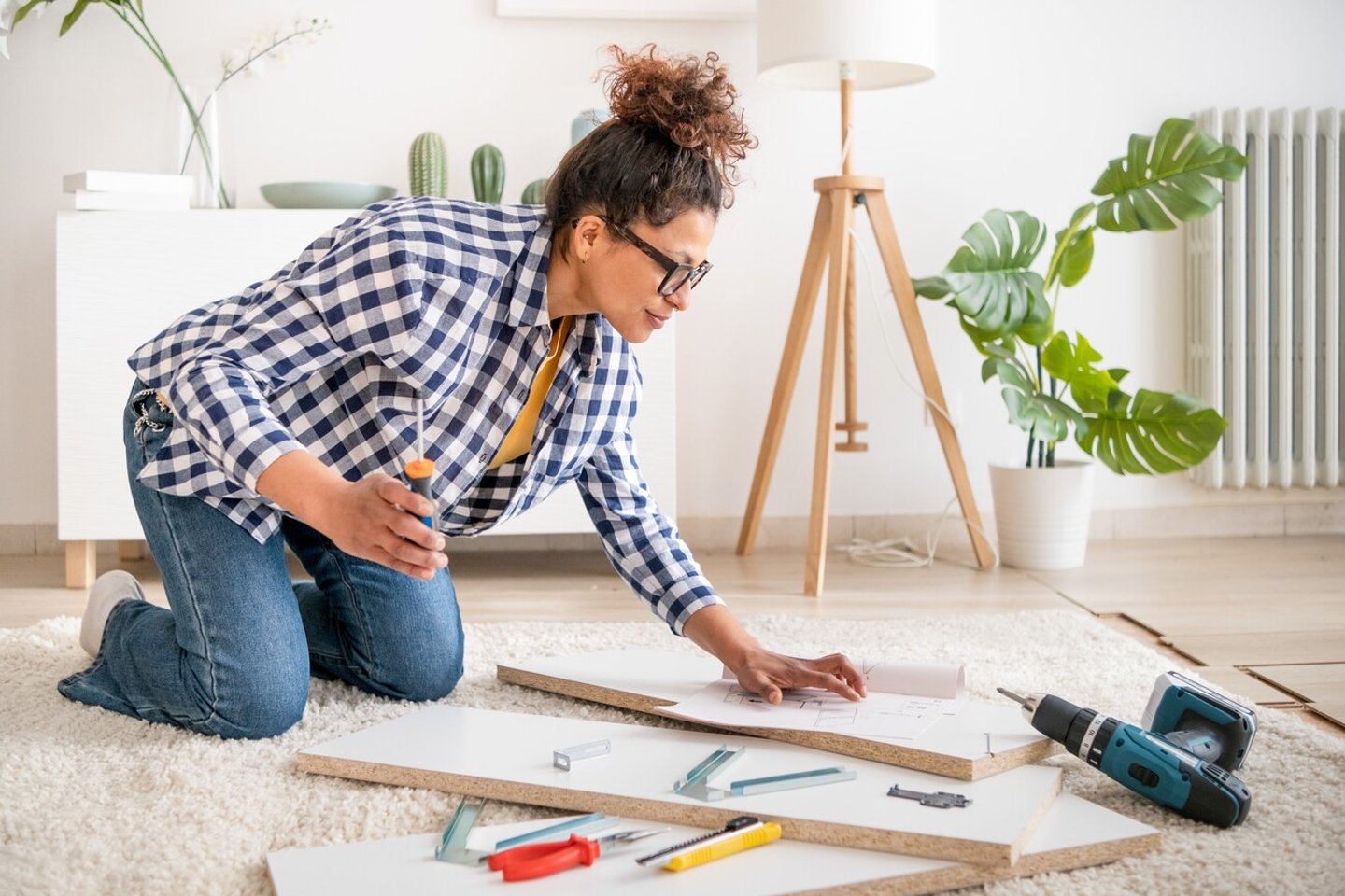Black woman doing home improvements using screwdriver in new home; Shutterstock ID 2251326145