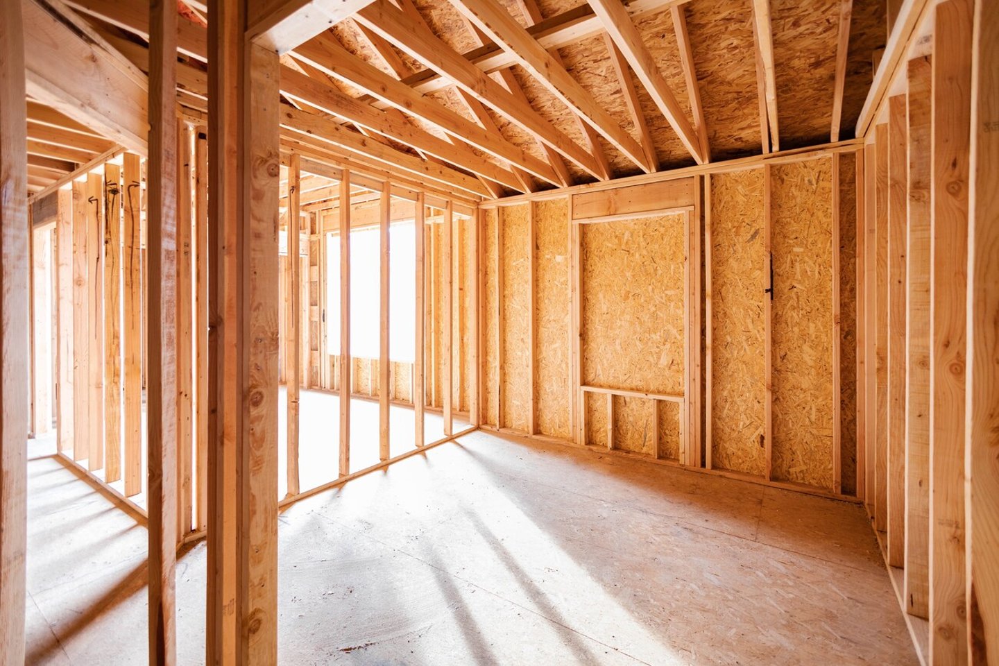 Wood framing and flooring structure with golden sunlight shining through window frame at empty room. New construction house, framework of real estate development industry. Renovation, building concept; Shutterstock ID 2264578825