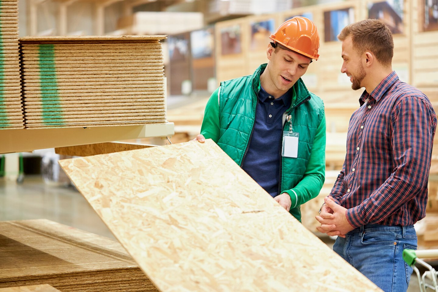 warehouse worker show the best variant of wooden board in their market, customer looking for building material; Shutterstock ID 1714746892