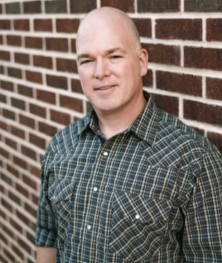 a man standing in front of a brick wall