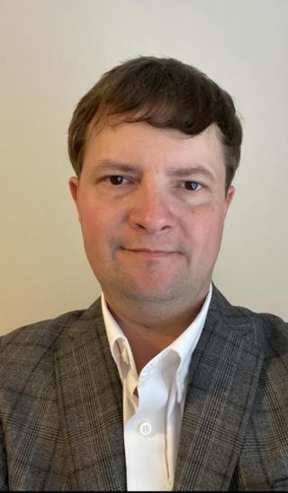 a man wearing a suit and tie smiling at the camera