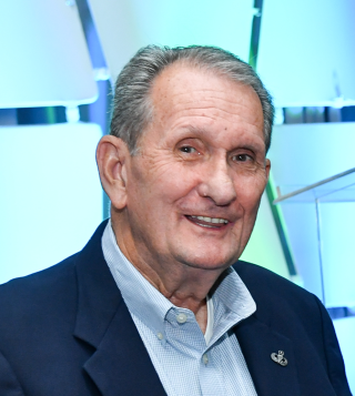 a man wearing a suit and tie smiling at the camera