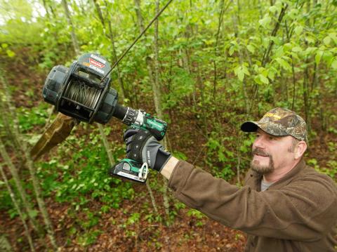 Metabo drill a man wearing a helmet standing next to a forest